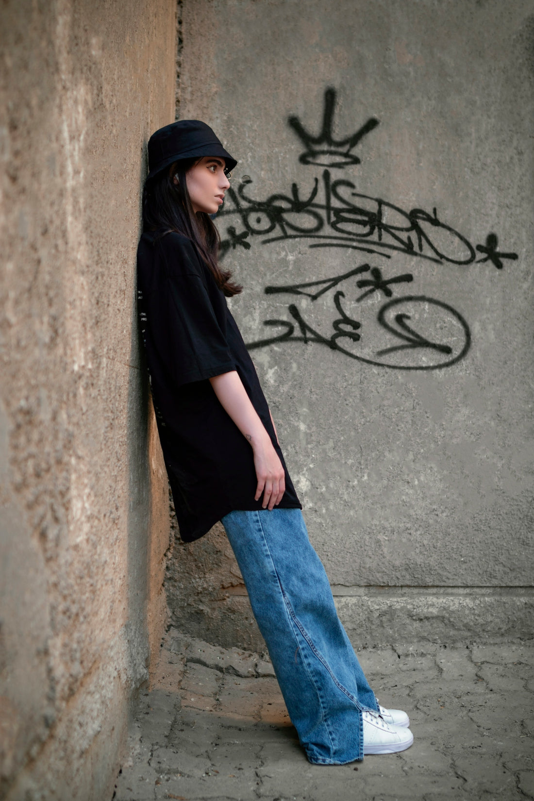 a woman leaning against a wall with graffiti on it